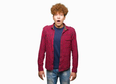Afro saç ile genç yakışıklı öğrenci adam korkuyor ve sürpriz ifade, korku ve heyecanlı yüz ile şok bir ceket giyiyor.