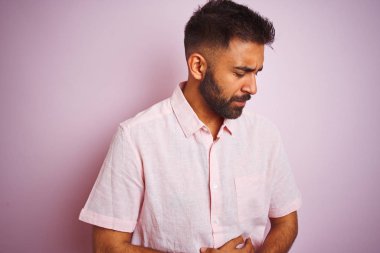 Bulantı, ağrılı hastalık hissi bozulmamış çünkü mide el ile izole pembe arka plan üzerinde ayakta rahat gömlek giyen genç Hintli adam. Ağrı kavramı.