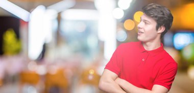 İkna ve kendine güvenen tarafına silahlarla seyir gülümseyen izole arka plan üzerinde kırmızı t-shirt giyen genç yakışıklı adam geçti