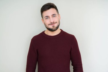 Genç yakışıklı adam komik yüz ile izole arka plan kabarık yanakları üzerinde bir kazak giyiyor. Ağız hava ile şişirilmiş, çılgın ifade.