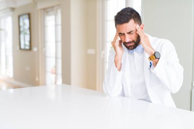 Yakışıklı İspanyol doktor veya terapist adam ağrı ve migren çünkü baş ağrısı çaresiz ve vurguladı klinikte tıbbi ceket giyiyor. Eller baş.