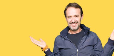 Gülen iki elle gösterilen avuç içi, sunma ve karşılaştırma ve denge reklam açık bir ceket giyen orta yaş yakışıklı adam