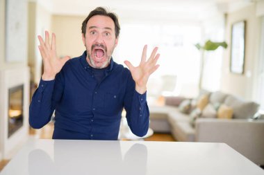 Yakışıklı orta yaş adam evde deli ve başarı için hayran kaldırdı Kollarını açarak kutluyor ve heyecanlı çığlık gözleri açık. Kazanan kavramı