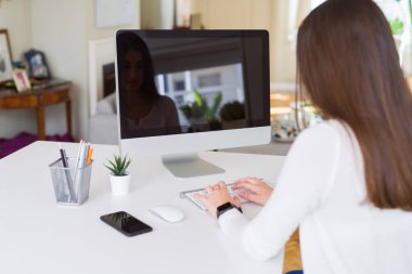 Bilgisayar kullanarak çalışan ve arka planda boş bir ekran gösteren gülümseyen genç kadın