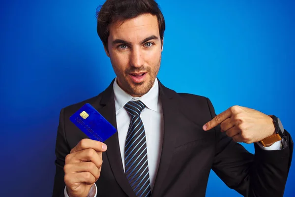 Mladý Pohledný Obchodník Držící Kreditní Kartu Stojící Nad Izolovaným Modrým — Stock fotografie