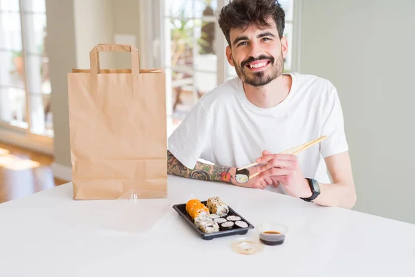 Young man eating sushi asian food and noodles using choopsticks