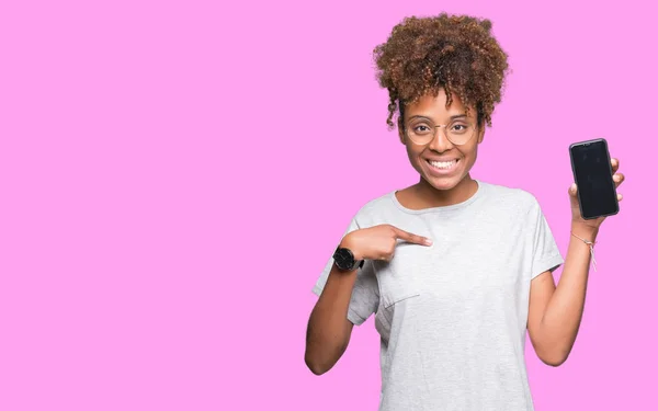 年轻的非洲裔美国妇女在孤立的背景显示智能手机屏幕与惊喜的脸指向自己的手指 — 图库照片