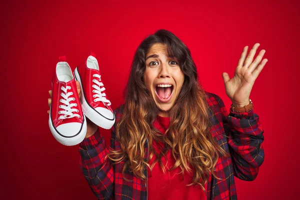 Jovem Mulher Bonita Segurando Tênis Sobre Fundo Isolado Vermelho Muito — Fotografia de Stock