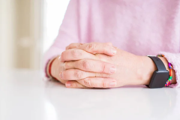 Gros plan de femme d'âge moyen mains croisées sur la table blanche — Photo