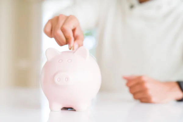 Hombre poniendo una moneda dentro de alcancía ahorro para la inversión — Foto de Stock