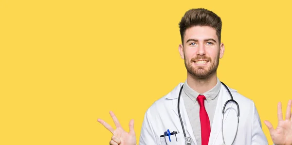 若いハンサムな医者男着て医療コート表示と指で上向き数 自信を持って 幸せな笑みを浮かべて — ストック写真