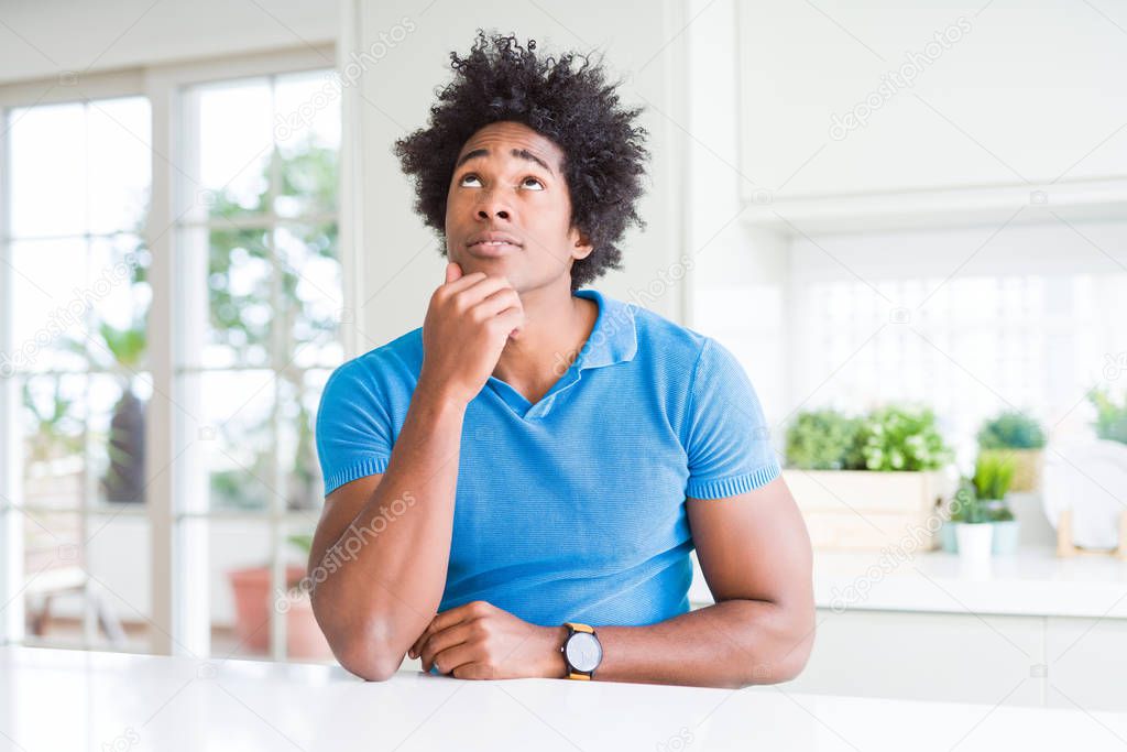 African American man at home with hand on chin thinking about question, pensive expression. Smiling with thoughtful face. Doubt concept.
