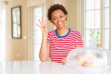 Evde Genç güzel Afrikalı Amerikalı kadın gösteren ve parmak sayısı dört ile işaret kadar güven ve mutlu gülümseyen.