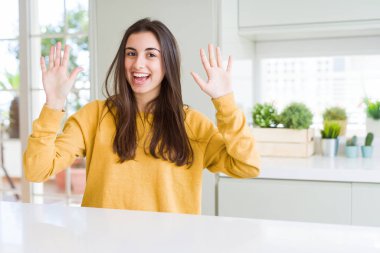 Sarı kazak gösteren ve parmak numarası on ile işaret giyen güzel genç kadın güven ve mutlu gülümseyen iken.