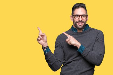 Gülümseyen ve iki elleri ve parmakları ile tarafına işaret kamera bakarak izole arka plan üzerinde gözlük takan genç yakışıklı adam.