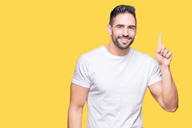 Başarılı fikirle izole arka plan üzerinde işaret parmağı rahat beyaz t-shirt giyen genç adam. Çıktıktan ve mutlu. Bir numara.