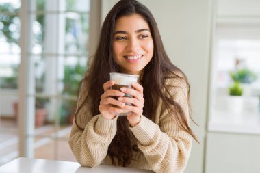 Güzel genç kız evde bir fincan kahve içme ve gülümseyen