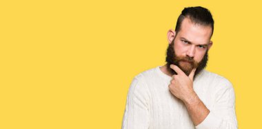 Emin çapraz kollar ve çeneme kaldırdı el ile gülümseme ile kameraya bakarak kış kazak giyen genç hipster adam. Pozitif düşünce.