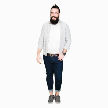 Uzun saç, sakal ve seksi bir ifadeyle, neşeli ve mutlu yüzünü kameraya bakarak göz kırpıyor küpe ile genç adam.