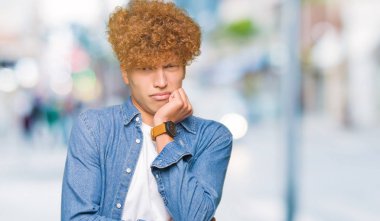 Afro saç ile genç yakışıklı adam denim ceket giymiş görünümlü vurguladı ve ağız ısırma çiviler eller ile gergin. Anksiyete sorunu.