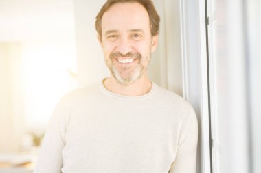 Evde kameraya bakarak gülümseyen yakışıklı orta yaş erkek