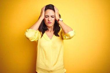 Sarı izole arka plan üzerinde duran güzel zarif kadın baş ağrısı çaresiz muzdarip ve ağrı ve migren nedeniyle vurguladı. Eller baş.