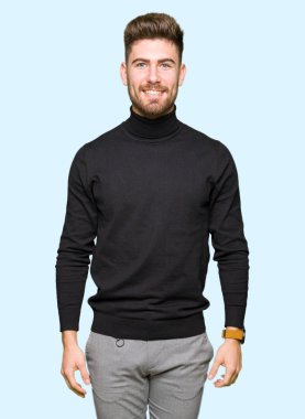 Yüzünde mutlu ve serin bir gülümseme ile kış kazak giyen genç yakışıklı sarışın adam. Şanslı kişi.