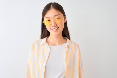 Genç Çinli kadın çizgili gömlek ve gözlük ile izole beyaz arka plan üzerinde mutlu bir yüz ayakta ve gülümsemek ile emin bir gülümseme dişleri gösteren giyiyor