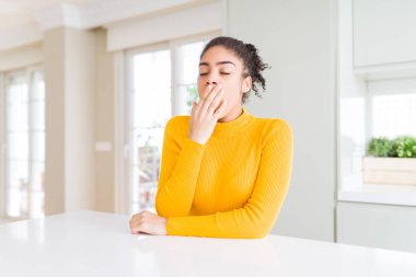 Afro saç ile güzel Afrikalı Amerikan kadın rahat bir sarı kazak elle yorgun kaplayan ağız ile sıkılayarak sıkılmış giyiyor. Huzursuz ve uykululuk.