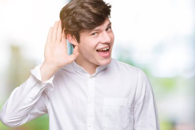 Genç yakışıklı iş adamı bir işitme söylenti ya da dedikodu için dinleme kulak üzerinde el ile gülümseyen izole arka plan üzerinde. Sağırlık kavramı.