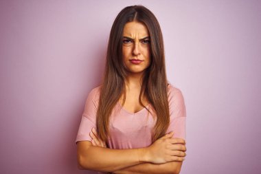 Genç güzel kadın izole pembe arka plan şüpheci ve sinir üzerinde duran t-shirt giyen, çapraz kolları ile yüzünde ifade onaylamayan. Negatif kişi.