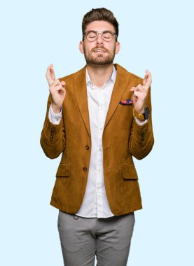 Umut ve gözleri kapalı geçiş parmaklarıyla gülümseyen gözlüklü genç yakışıklı iş adamı. Şans ve batıl kavramı.