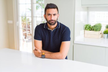 Evde yakışıklı İspanyol adam şüpheci ve sinir, kesişen silah ile yüz üzerindeki ifade onaylamaz. Negatif kişi.