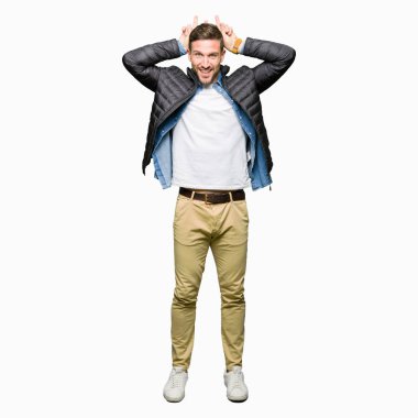 Neşeli gülümseyen kış ceket tavşan kulakları, komik ve çılgın baş parmaklar ile poz giyen yakışıklı adam