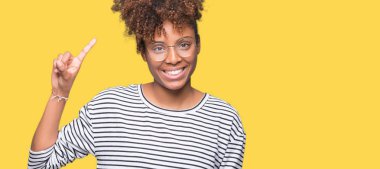 Güzel genç Afrikalı-Amerikalı kadın ve kendinden emin ve mutlu gülümseyerek süre parmak numaralı yukarıyı gösteren izole arka plan üzerinde gözlük.