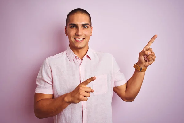 年轻的帅哥穿着优雅的衬衫在粉红色孤立的背景微笑 看着相机指着两只手和手指的一边 — 图库照片