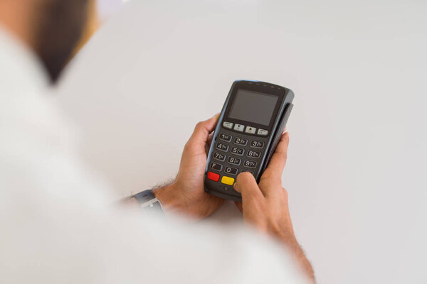 Close up of man hands holding point of sale terminal, dataphone 