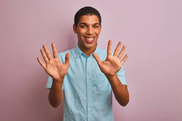 年轻的英俊阿拉伯男子穿着蓝色衬衫站在孤立的粉红色背景显示和指着手指数字十 同时微笑自信和快乐 — 图库照片