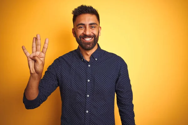 孤立した黄色の背景の上にシャツを着た若いハンサムなインドのビジネスマンは 自信を持って幸せに微笑みながら 指の4番を見せ 指を上げる — ストック写真