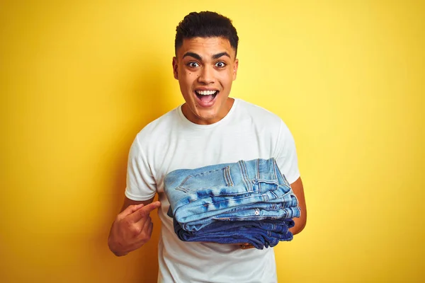 Jovem Lojista Brasileiro Homem Segurando Jeans Sobre Fundo Amarelo Isolado — Fotografia de Stock