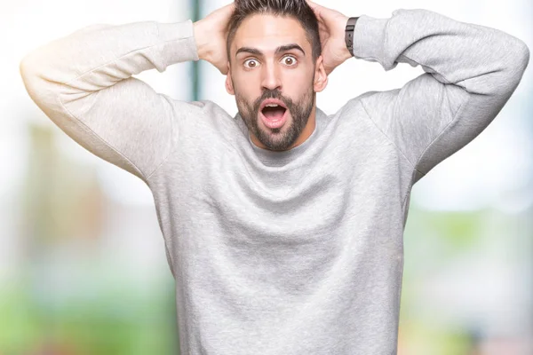 Young handsome man wearing sweatshirt over isolated background Crazy and scared with hands on head, afraid and surprised of shock with open mouth