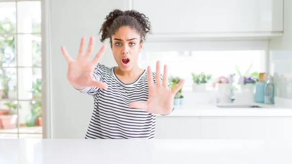 Beautiful african american woman with afro hair wearing casual striped sweater doing stop gesture with hands palms, angry and frustration expression