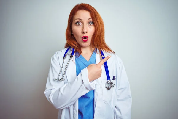 Joven Doctora Pelirroja Usando Estetoscopio Sobre Fondo Blanco Aislado Sorprendido —  Fotos de Stock