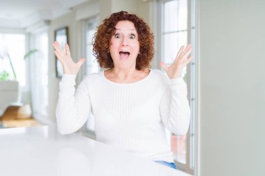 Beyaz kazak giyen güzel yaşlı kadın deli kutluyor ve kollarını kaldırdı ve açık gözleri heyecan çığlık ile başarı için hayran. Kazanan kavramı