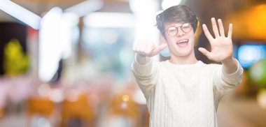 Gösterilen arka plan üzerinde gözlük takan genç yakışıklı adam izole ve parmakları ile işaret kendinden emin ve mutlu gülümseyerek süre 6 numara.