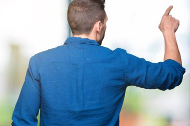 İzole genç yakışıklı adam arka plan geriye doğru arkasında parmak eliyle işaret Posing