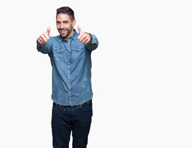 Yakışıklı delikanlı el ile pozitif jest yapıyor onaylama izole arka plan üzerinde başparmak gülümseyen ve başarı için mutlu. Kamera, kazanan jest arıyorsunuz.