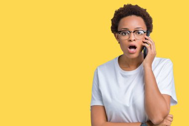 Genç Afro-Amerikan kadın telefonda izole arka plan üzerinde bir sürpriz yüz, korkuyor ve heyecanlı korku ifadesi ile şok korkmuş söz