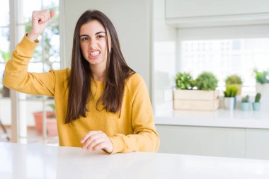 Güzel genç kadın sarı kazak kızgın ve deli yükseltme yumruk sinirli ve öfkeli kızdırmak ile bağırırken giyiyor. Öfke ve agresif kavram.