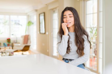 Genç güzel kadın evde stresli ve gergin elle çivi ısırma ağzına bakıyor. Anksiyete sorunu.